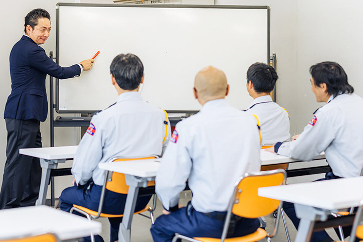 ホワイトボートの前で、研修担当者が座学の講習を行っている様子