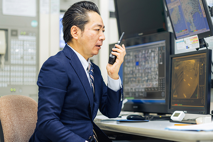 保安担当者が、監視モニターの前でトランシーバーで指示を送っている様子